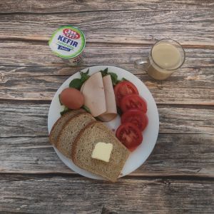 Zdjęcie przedstawia Dietę z ograniczeniem łatwoprzyswajalnych węglowodanów: Chleb Graham Masło extra Jajko gotowane Kawa zbożowa z mlekiem Kefir Pomidor Filet zapiekany drobiowy Roszponka